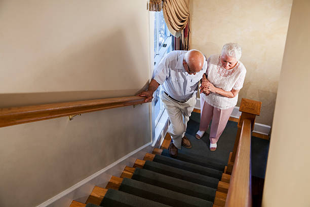 senior frau helfende mann klettern treppe - stair rail stock-fotos und bilder