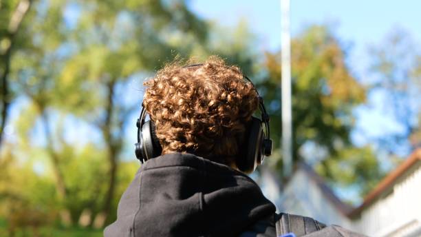 istock Caucasian guy with headphones and backpack walking through a public park during sunny day. Lifestyle. Concept of autumn walks. Slow motion 1705926581