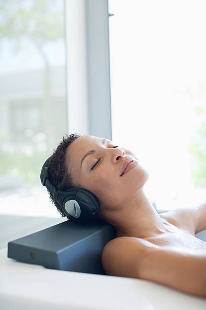 mujer escuchando música en la bañera - escape from it all audio fotografías e imágenes de stock
