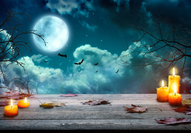 istock Spooky Halloween pumpkins, Jack O Lantern, with an evil face and eyes on a wooden table with a misty  background and full moon. 1705936281