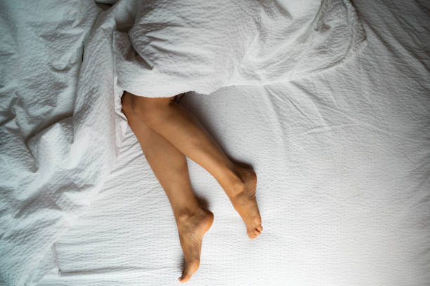 istock High angle view of female legs in bed 1705952719
