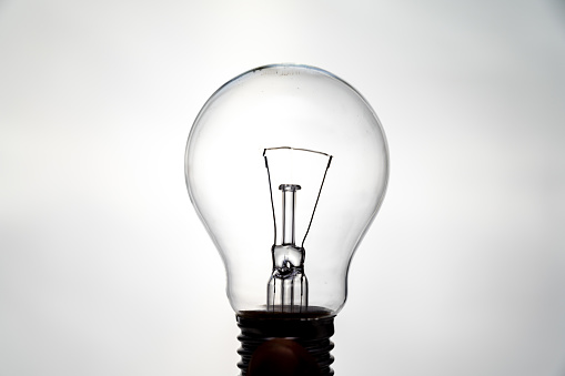 Incandescent light bulb, photographed against the light, which appears to be on. Electricity and renewable energy sources.