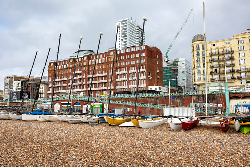 Brighton, United Kingdom - Sep 26, 2023: Boats lined up in Brighton Beach in United Kingdom. People can be seen sitting by the shore.