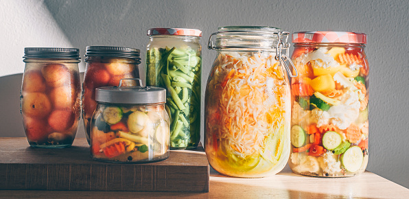 Probiotics fermented food background. Green beans, mixed vegetables , sauerkraut, pickled plums in glass jars. Winter fermented and canning food concept, homemade preparations, home pharmacy. Banner