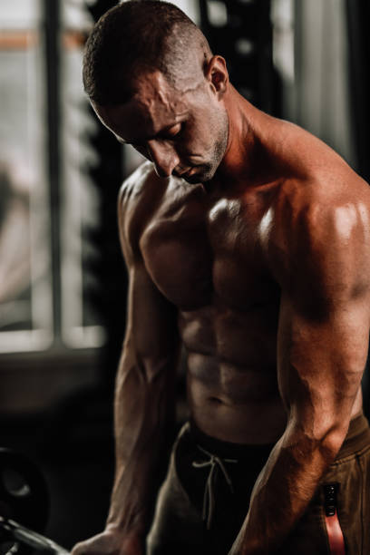 istock Male Bodybuilder Stretching Out Biceps In Gym With Barbell 1705970387