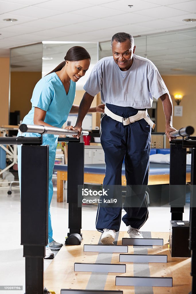 Gait training physical therapy Physical therapist (40s) helping patient (60s) through gait training. Physical Therapy Stock Photo