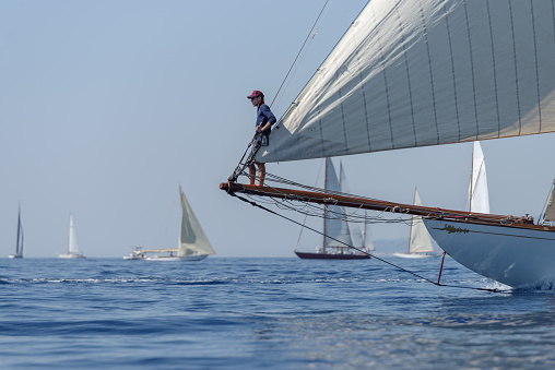 Imperia, Italy - September 10, 2023: Crew member aboard on sailboat during regatta in Gulf of Imperia. Established in 1986, the Imperia Vintage Yacht Challenge Stage is a of the most important event in sailing the Mediterranean dedicated to historical boats