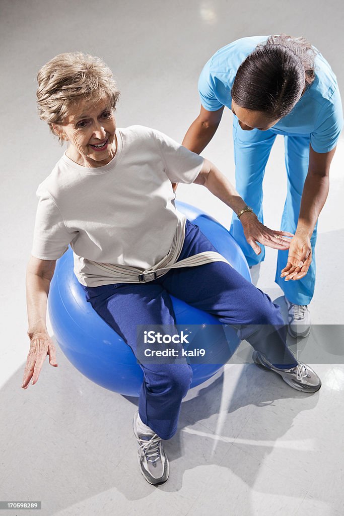Kinésithérapeute avec Femme âgée sur un ballon d'exercice - Photo de Vue en plongée libre de droits