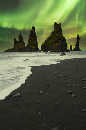 Beautiful Landscape of Black Pebbles Beach with Northern Lights. Amazing View on the Basalt Cliffs and the Sea. Vik Myrdal. Iceland