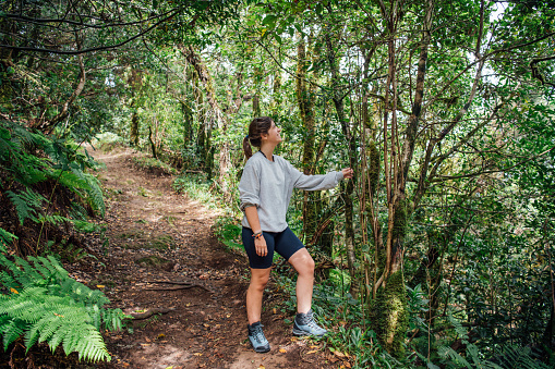 A young hiker rests by the trail smiling in nature