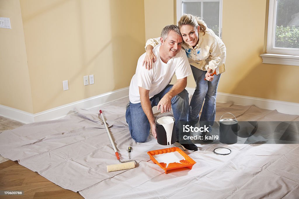 Couple painting home interior Couple (30s, 40s) painting walls inside home, pouring paint into tray. 30-39 Years Stock Photo