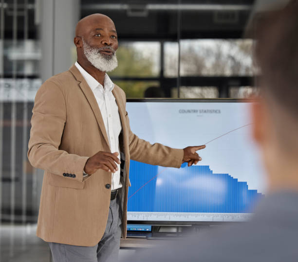 istock Mentorship, black man teaching or business people in presentation for data report or financial analysis. Pointing, leader or senior manager in meeting with graphs stats on screen monitor in training 1706007904