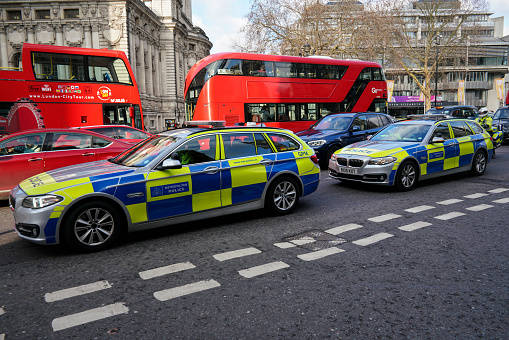 London, United Kingdom - February 02, 2019: Blue and green metropolitan police cars patrolling at Westminster area, typical  doubledecker red buses in background