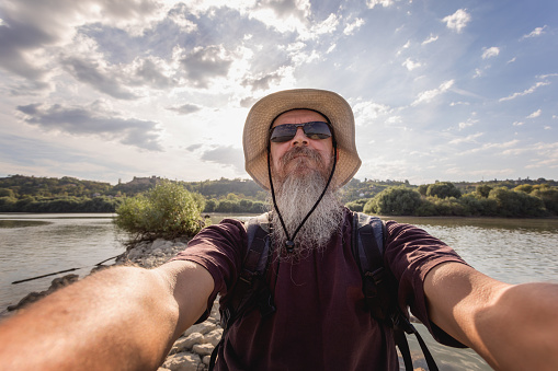 50 year old sports fisherman at fishing ground on Danube river smiling at camera, selfie