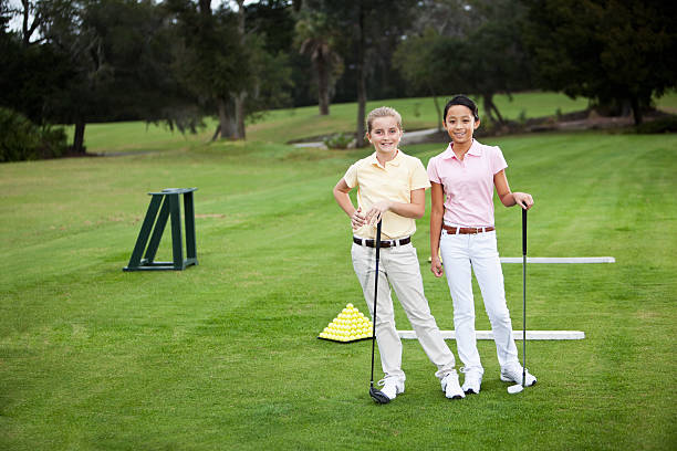 niñas de pie en un campo de práctica de golf - sc0529 fotografías e imágenes de stock