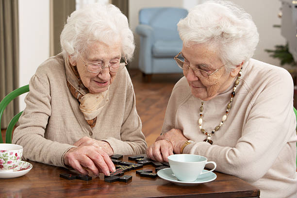 deux femmes âgées jouant aux dominos à jour centre de soins - senior adult independence lifestyles home interior photos et images de collection