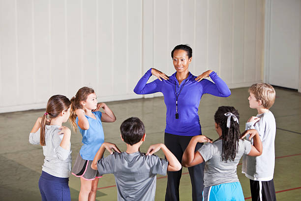 Physical education class African American woman (30s) teaching a physical education class with elementary age children (7-9 years). physical education stock pictures, royalty-free photos & images