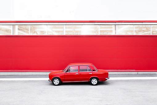 old retro red car parker near the red wall, nostalgic transportation concept