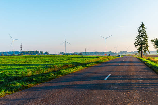 paisaje durante la puesta de sol con carretera, campo y turbinas eólicas. molinos de viento para la producción de energía. la carretera asfaltada con turbinas eólicas durante la puesta de sol. - 7583 fotografías e imágenes de stock