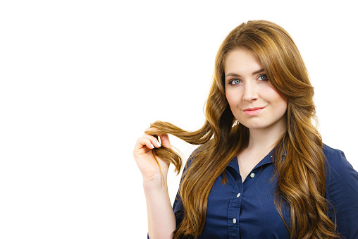 Young woman with long hair shows healthy ends, on white