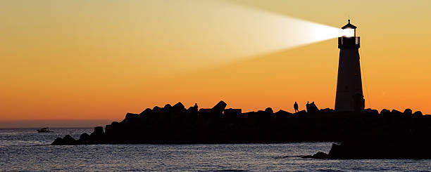 istock Lighthouse on a rocky shore silhouetted against the sunset 170608671