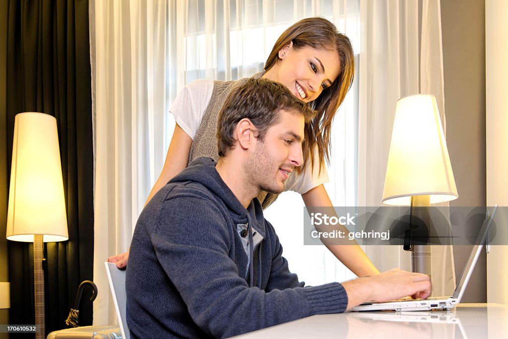 Casal jovem, usando o computador em um quarto de hotel - Foto de stock de 20-24 Anos royalty-free