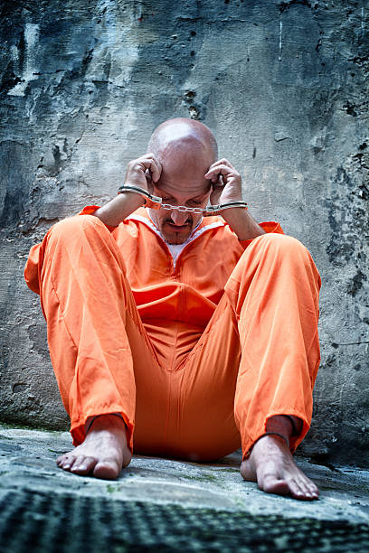 istock Handcuffed Prisoner in Orange Coveralls 170611587