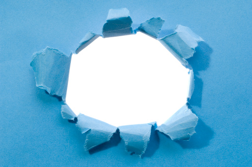 A hole punched into blue paper.