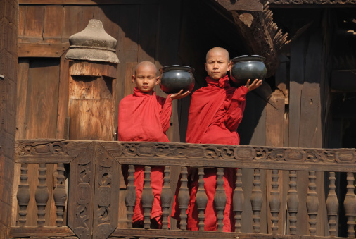 Two novice monks carrying their food bowls