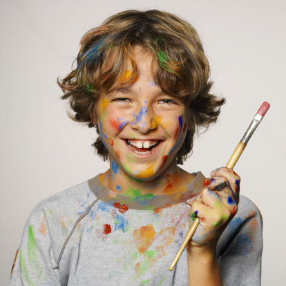 Young boy with brush covered in paint making funny face.More like this :