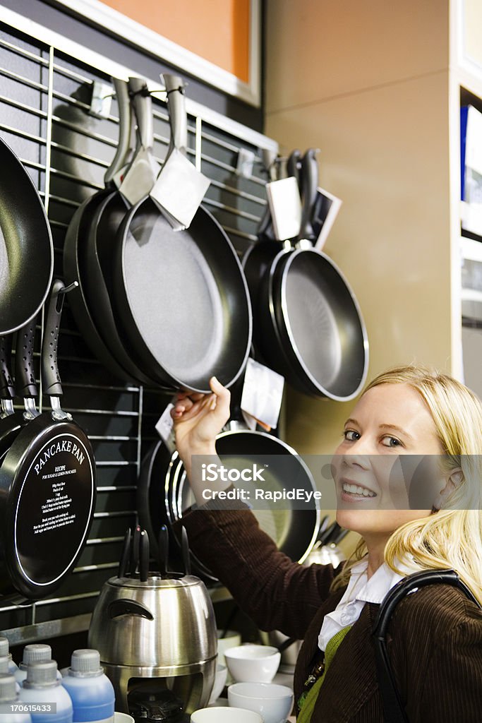 Shopping for kitchenware Young blonde woman checks out the frying pans in the kitchenware section of a department store.Camera: Canon 5D.20 pictures of this model shopping at the mall (these thumbnails are just a sample): Frying Pan Stock Photo