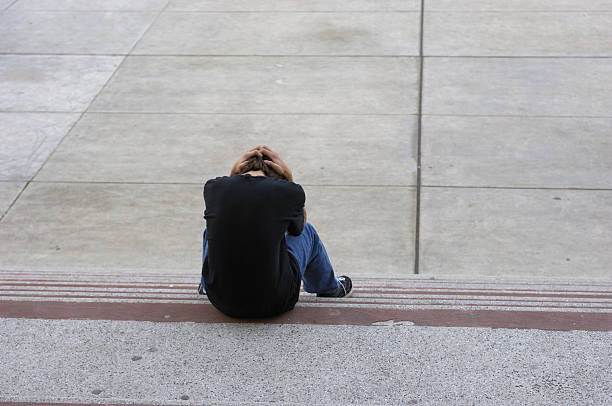 Sad teenager boy sitting at floor at the corridor