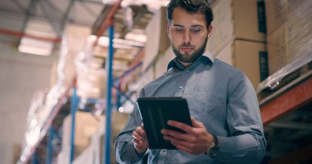 istock Tablet, manager or warehouse man reading inventory data of box storage, logistic cargo or industrial distribution info. Delivery stock, factory plant or person check shipping order, backlog or export 1706156490