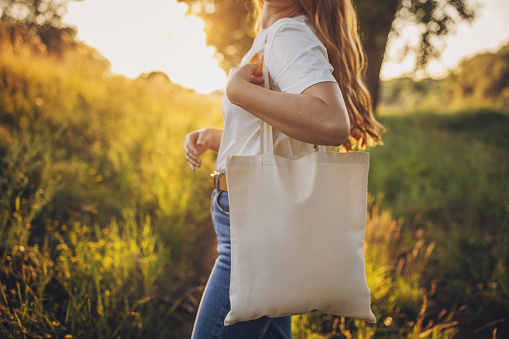 One woman, modern woman with reusable bag standing in nature.