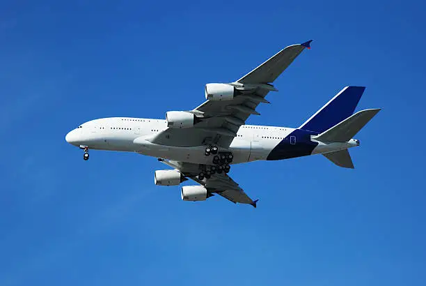 Giant airbus A380 airplane with landing gear out on a clear blue sky.