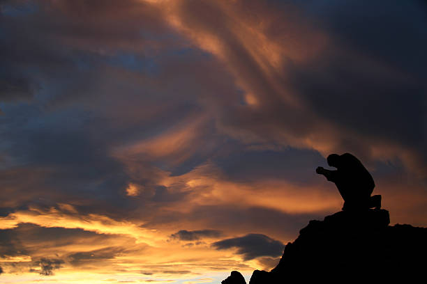 istock Silhouette of a Man Kneeling and Praying on Mountain 170615993