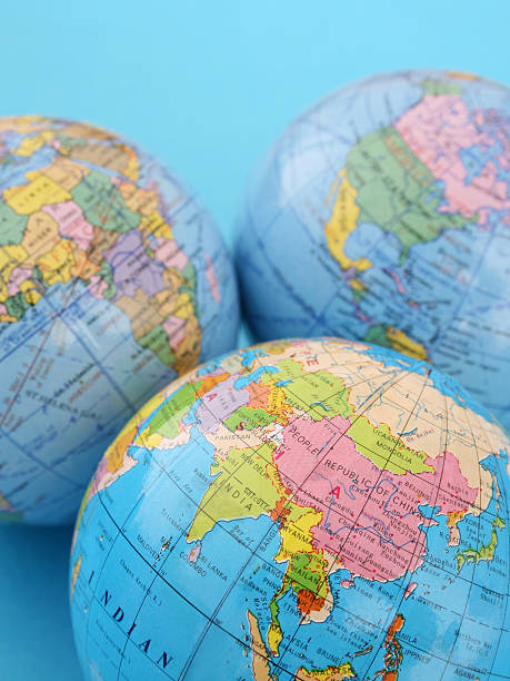Focus on Asia Three cheap plastic globes together showing continents over blue background. Shallow depth of field, focus on image bottom desktop globe stock pictures, royalty-free photos & images