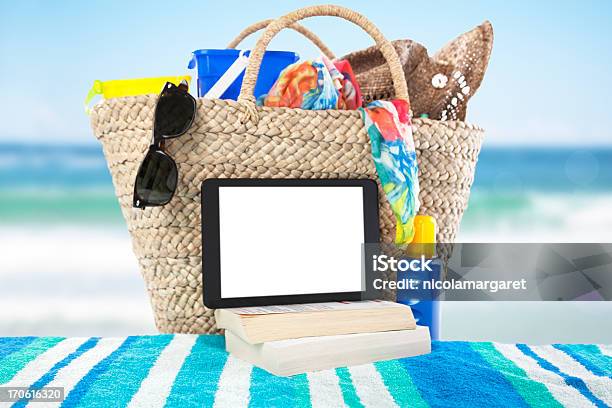 A Digital Tablet And Books On A Beach Towel At The Ocean Stock Photo - Download Image Now