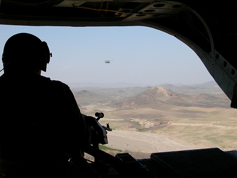 This picture is taken looking out the rear of a US Chinook helicopter while flying over south eastern Afghanistan between Tarin Kowt and Kandahar.  The picture was taken on 28 Feb 07.  The other helicopter is one of the two Apache escorts.  The Apache appears blurry due to the hot exhaust coming from the Chinook.
