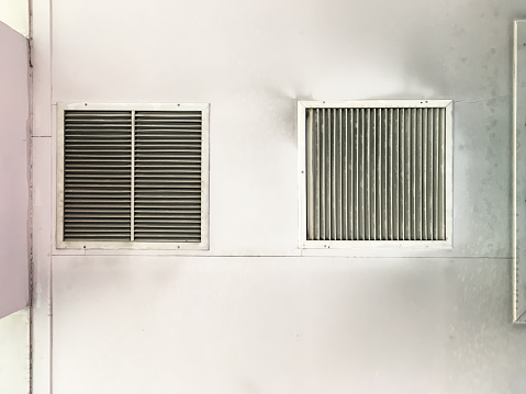 The metal grille is covering the air condition vent of the air conditioning system in the old office building, front view for the background.