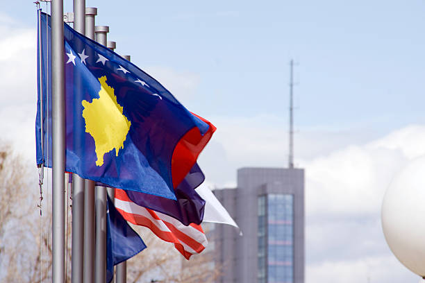 Flag of Kosovo The new flag of Kosovo waving in the capital city Prishtina, with Parliament building (Assembly of Kosovo) in background. pristina stock pictures, royalty-free photos & images