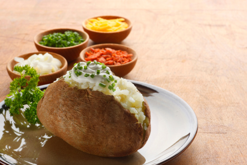 A baked potato with sour cream and chives.