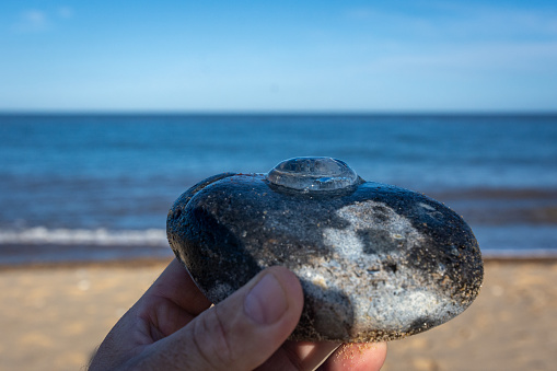Man holding round stone in hand resting on the seaside during vacation.