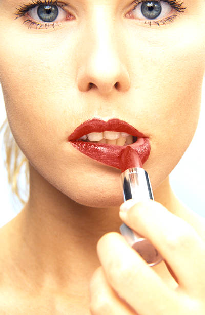 istock woman putting on red lipstick 170617110