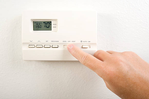 Close-up of hand operating the home heating system controls stock photo