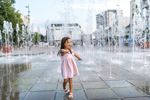Girl playing in fountain in summer day