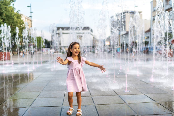 Girl playing in fountain in summer day