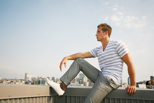 Young adult man sitting in front of the sky