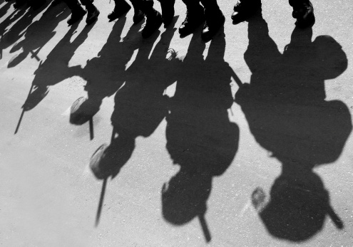 Shadows of riot police on a city street.
