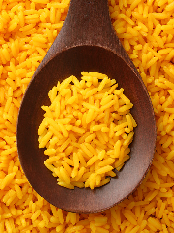 Top view of wooden spoon full of boiled saffron rice